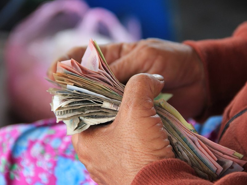 A person counts a stack of paper currency.