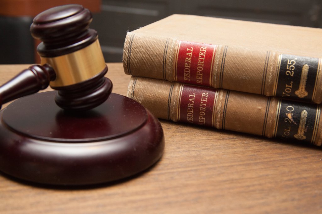 Judge's gavel in a courtroom with a stack of law books